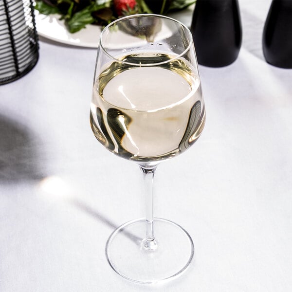 A Reserve by Libbey Prism wine glass filled with white wine on a table.