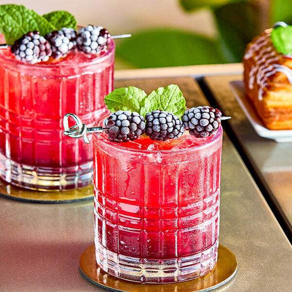 Two glasses of red drinks with blackberries on the rim.