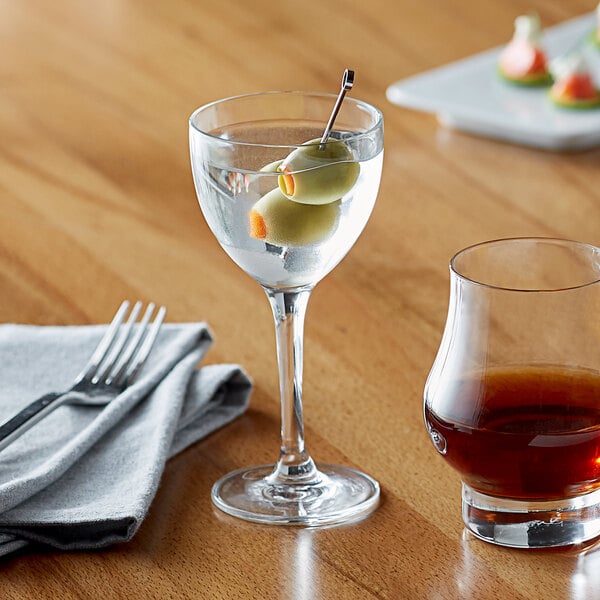 A Reserve by Libbey Nick and Nora glass of brown liquid with an olive in it on a table.