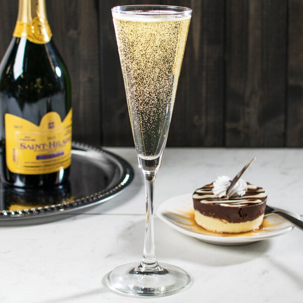 A Libbey trumpet flute filled with champagne on a table with chocolate cake.
