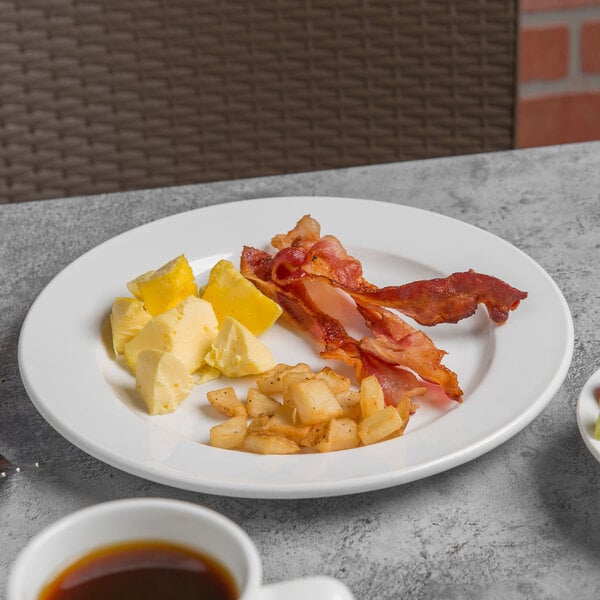 A Libbey Porcelana white porcelain plate with bacon, eggs, and coffee on a table.