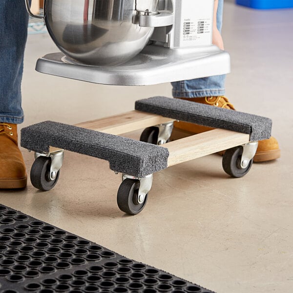 A person standing on a Lavex wood dolly with a machine on it.