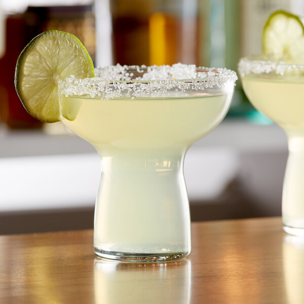Two Libbey Symbio cocktail glasses filled with a drink and garnished with a lime wedge.