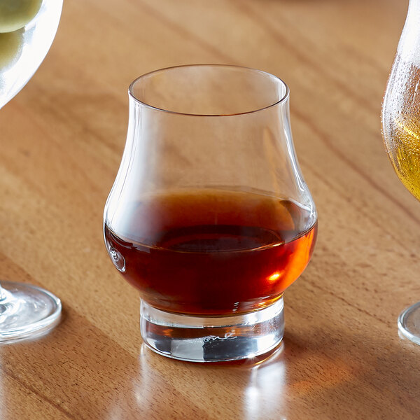 A Reserve by Libbey Circa whiskey glass filled with brown liquid on a table.