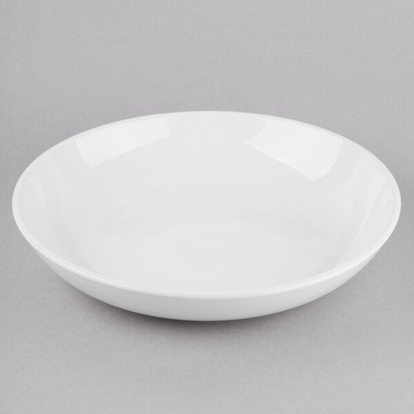 A Libbey Porcelana bright white porcelain low bowl on a gray surface.