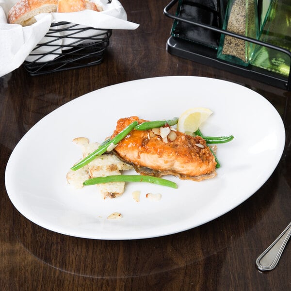 A Libbey white oval coupe platter with food on a table.