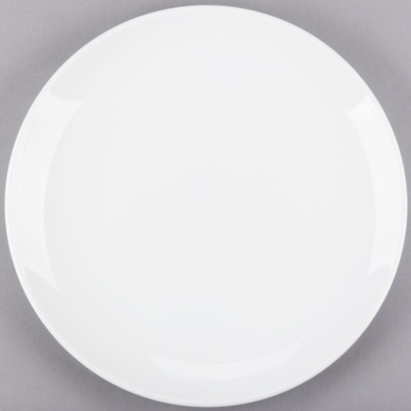 A Libbey Porcelana bright white round porcelain coupe plate on a gray surface.