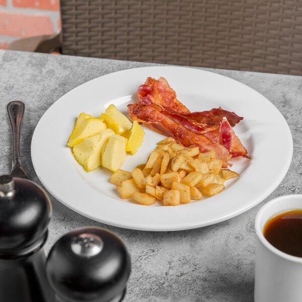 A Libbey Porcelana round white plate with bacon, eggs, and coffee on a white surface.