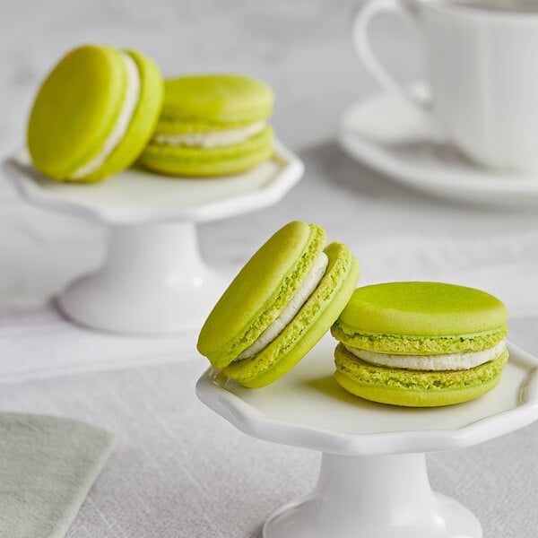 A green and white macaroon on a white stand.