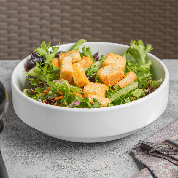 A Libbey Porcelana bright white porcelain bowl filled with salad and croutons.