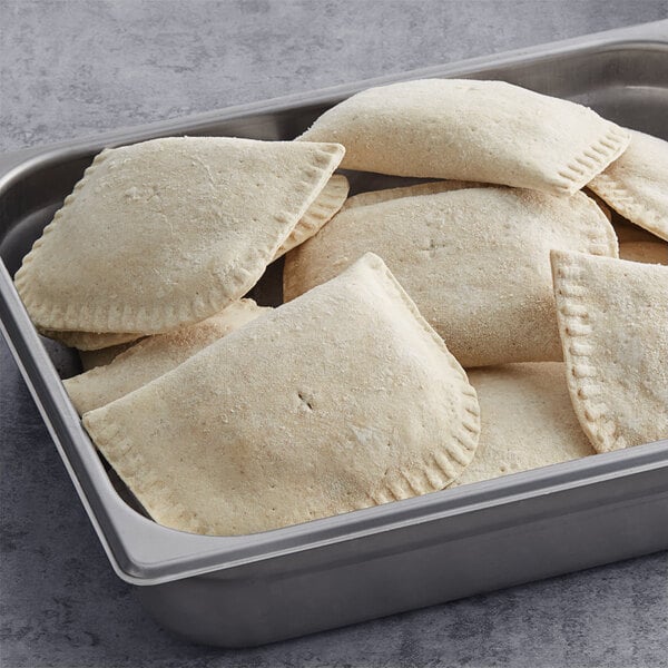 A metal container filled with unbaked Caribbean Food Delights vegetable patties.