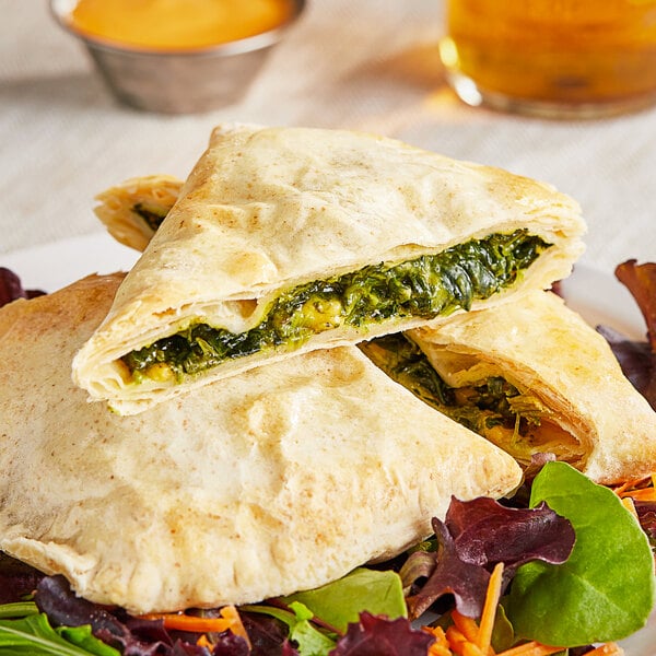 A plate with a Caribbean Food Delights Unbaked Spinach and Cheese Patty on it.