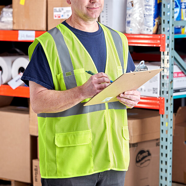 A man in a Lavex lime high visibility safety vest writing on a clipboard.