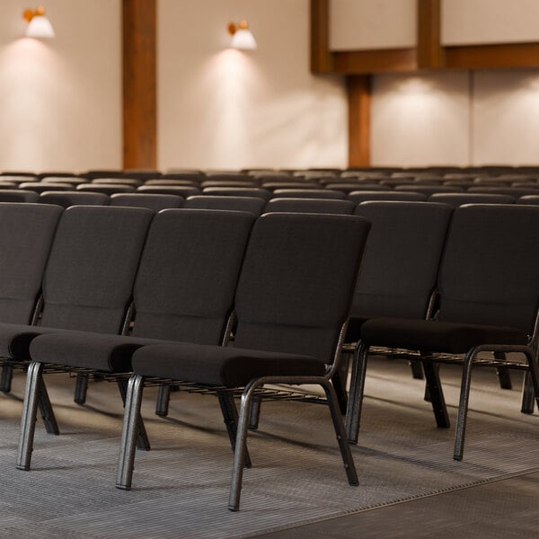 Lancaster Table & Seating silver vein church chairs with black fabric in rows in a room.