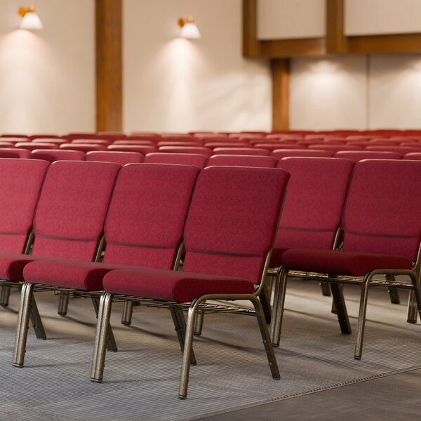 A row of Lancaster Table & Seating church chairs with burgundy fabric in a room.
