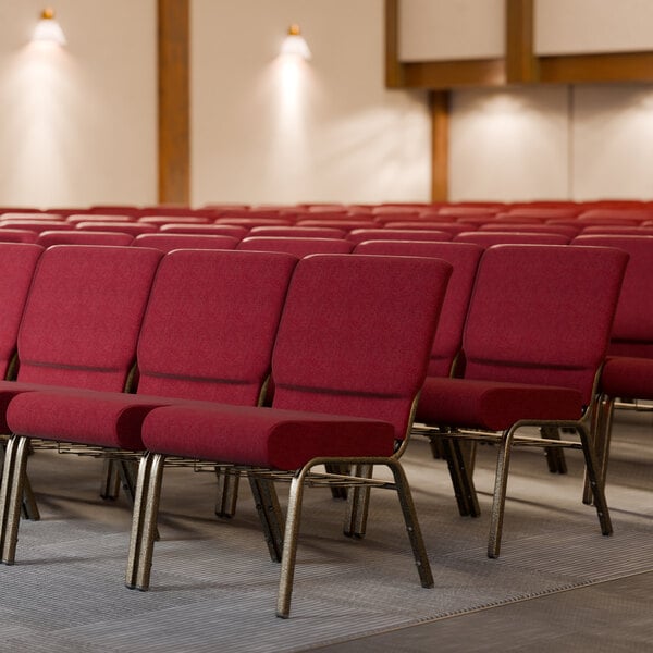 A room with rows of Lancaster Table & Seating church chairs with burgundy fabric.
