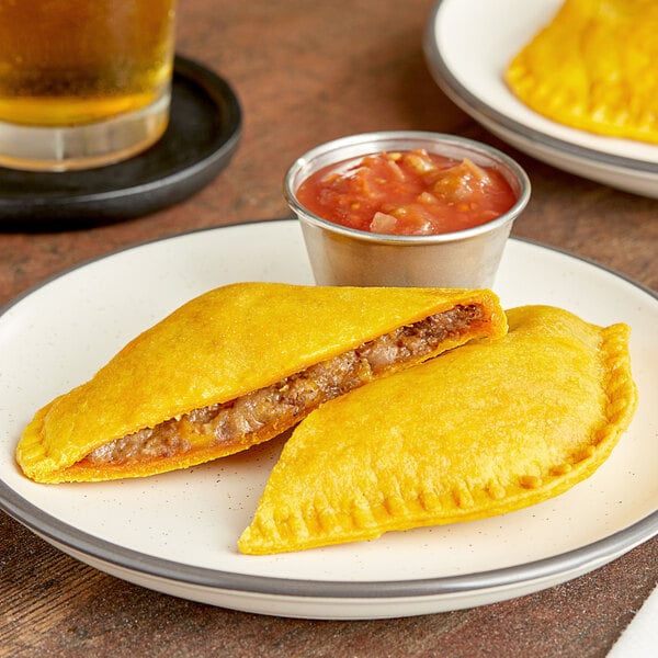 Two unbaked Caribbean Food Delights Beefy Cheese patties on a plate.