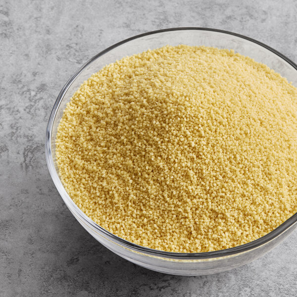A bowl of couscous on a gray surface.