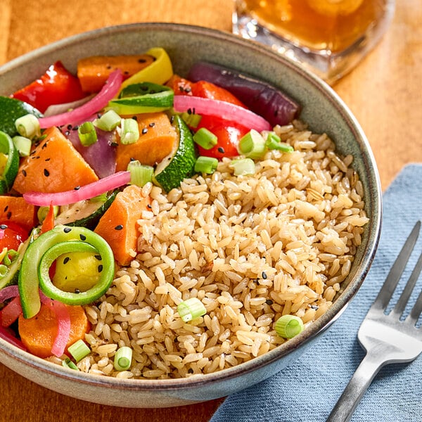 A bowl of Parboiled Brown Rice and vegetables with a fork.