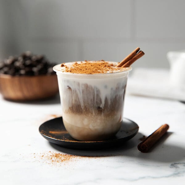A Tossware Natural rounded bottom cold cup filled with coffee and cinnamon sticks.