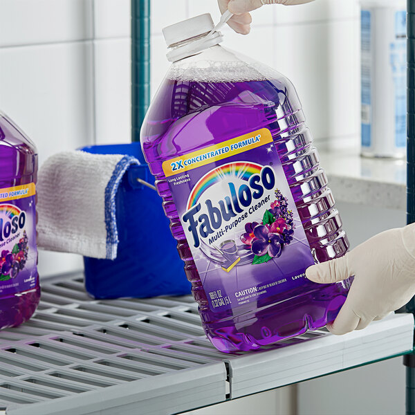 A person holding a large bottle of Fabuloso lavender scented purple liquid.