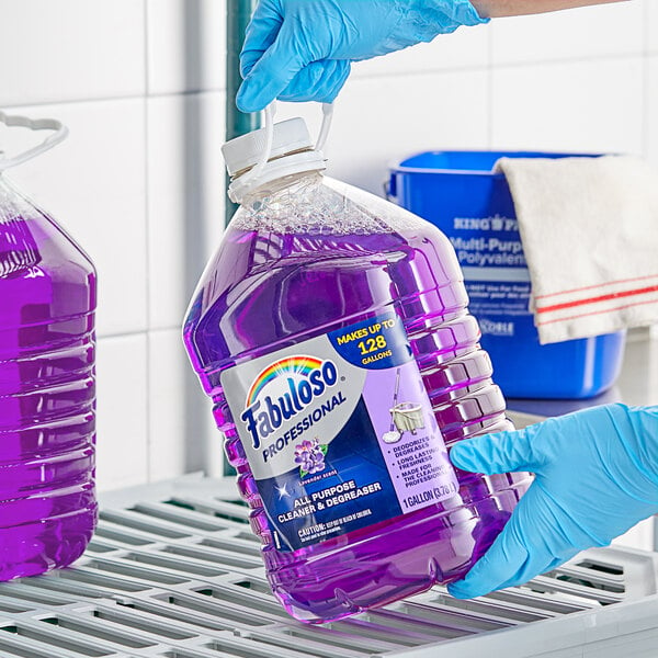 A gloved hand holding a large jug of Fabuloso lavender all-purpose cleaner.