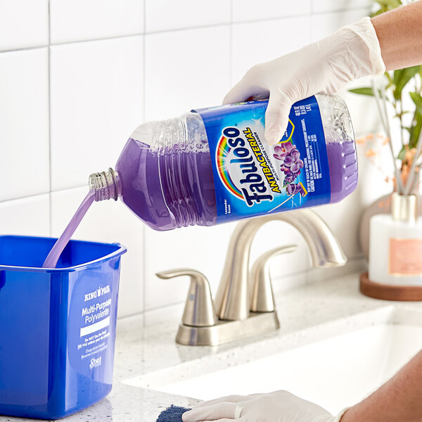 A hand pouring Fabuloso Lavender Scent multi-purpose cleaner into a blue container.