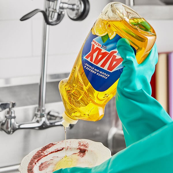 A person in gloves pouring Ajax Ultra Lemon Scent dish soap into a bowl.