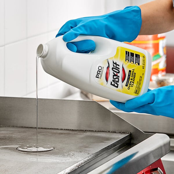 A person in blue gloves pouring Easy-Off liquid into a stove.