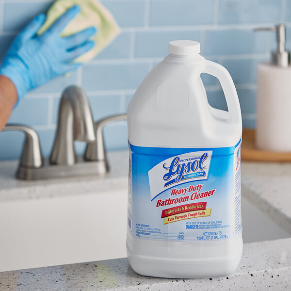 A person wearing blue gloves using Professional Lysol Disinfectant Heavy-Duty Bathroom Cleaner to clean a bathroom sink.