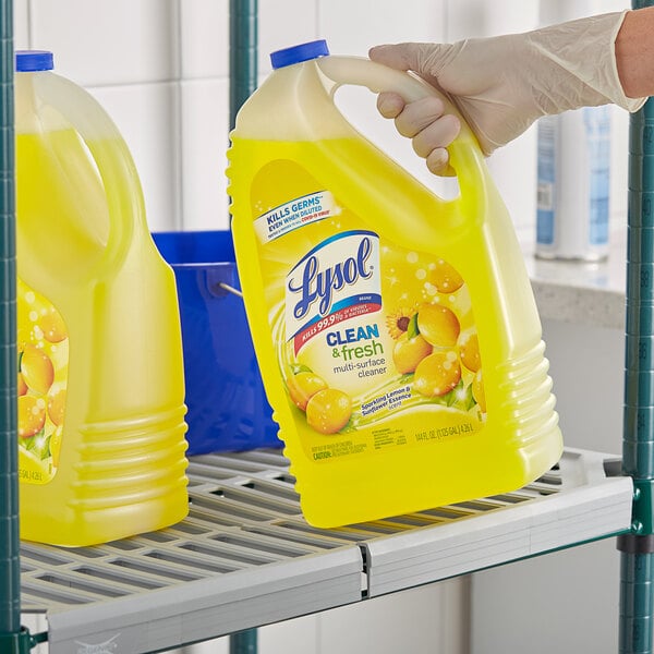 A hand holding a yellow bottle of Lysol multi-surface cleaner.