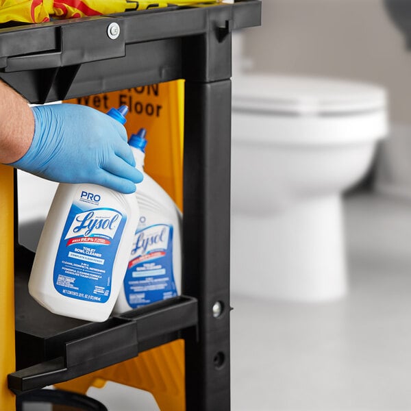 A hand in a blue glove holding a white bottle of Professional Lysol Toilet Bowl Cleaner.