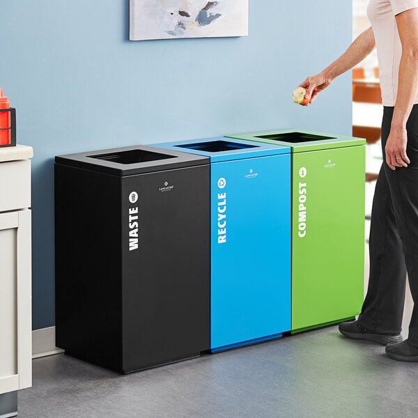 A woman standing next to a green Lancaster Table & Seating compost bin.