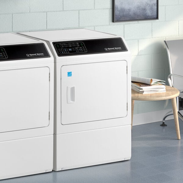 A white Speed Queen front load dryer next to a white chair.