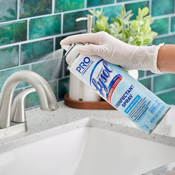 A person in gloves spraying Professional Lysol disinfectant on a white surface.