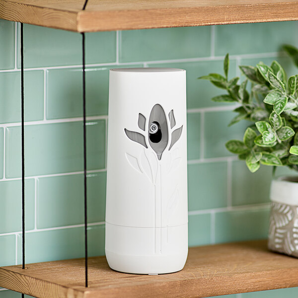 An Air Wick Freshmatic air freshener in a white container on a shelf.