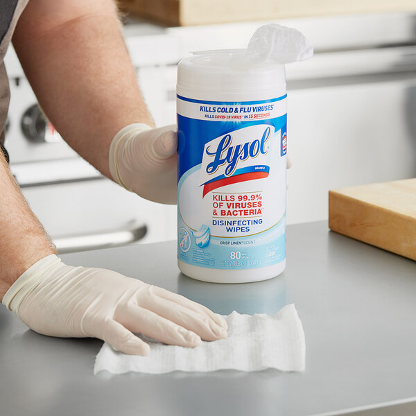 A gloved hand using Lysol Disinfecting Wipes to clean a kitchen counter.