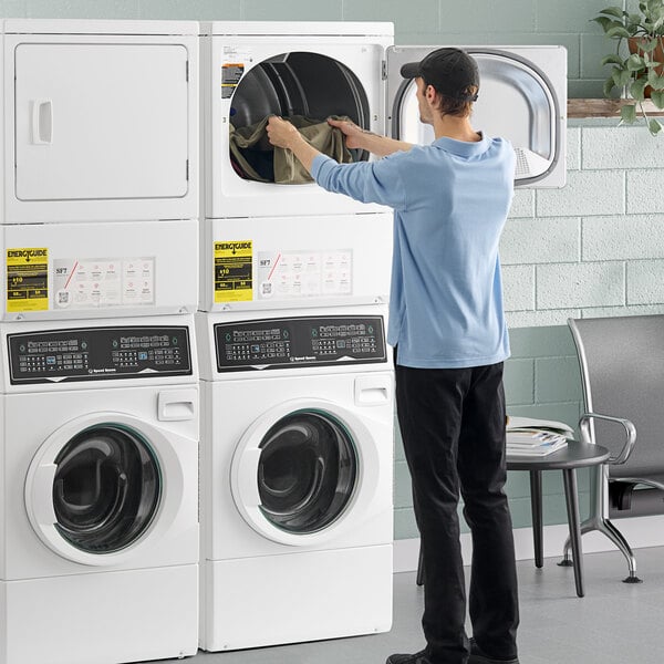 A stacked Speed Queen front load washer and dryer unit with a person loading laundry into the dryer.