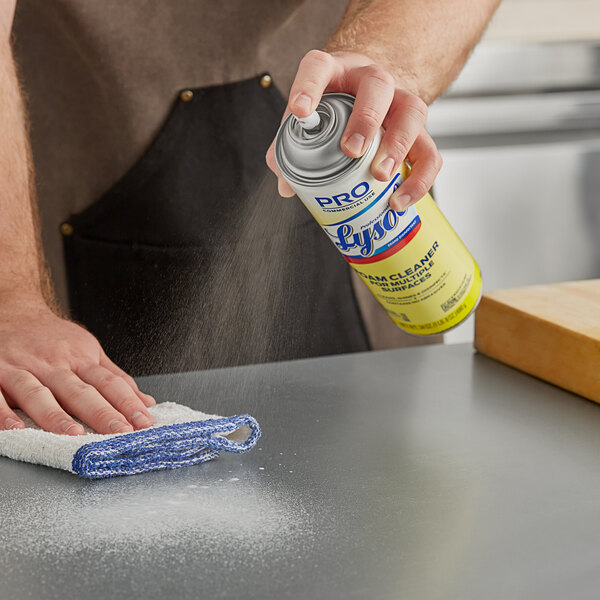 A person using Professional Lysol Foam Cleaner to disinfect a counter.