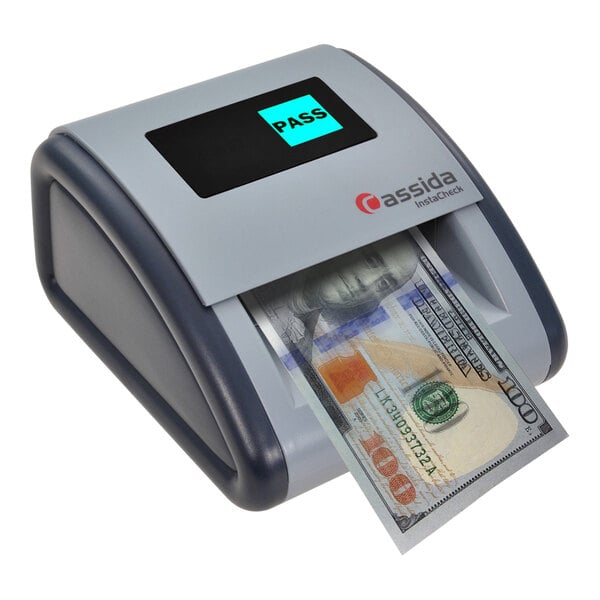 A Cassida InstaCheck counterfeit detector on a counter with a dollar bill.