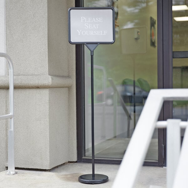 A black Aarco changeable poster sign on a sidewalk.