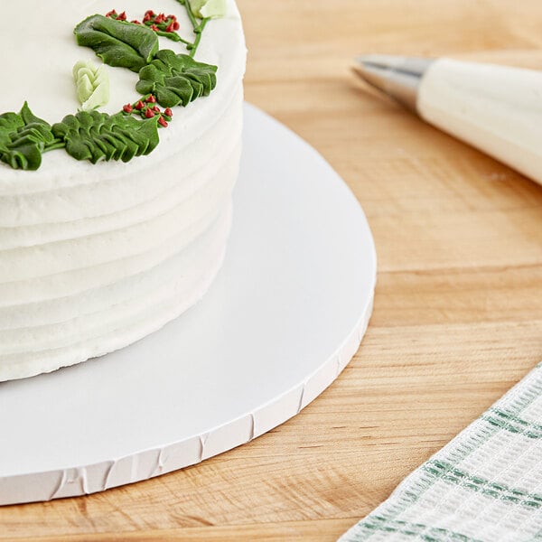 A close-up of a white cake with frosting on a Baker's Lane white cake drum.