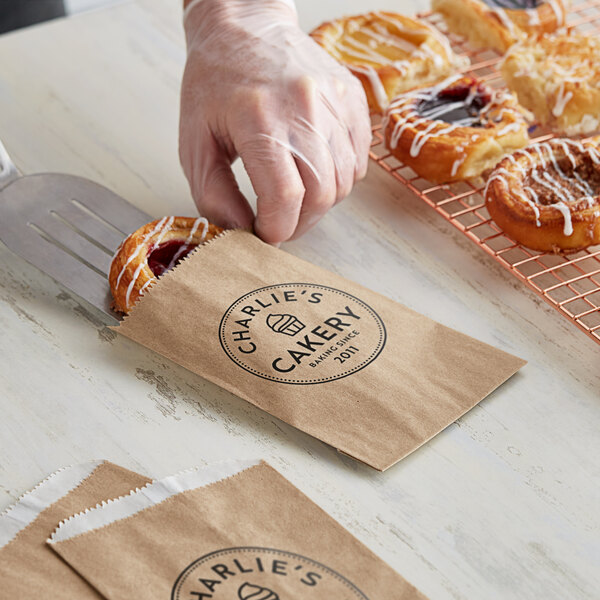 A person putting a pastry in a customizable kraft gourmet bag.