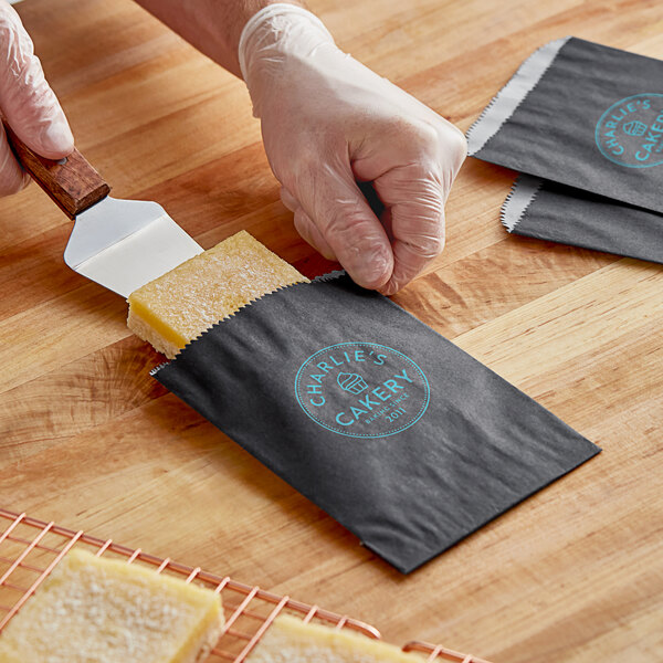 A hand putting food in a black paper bag.