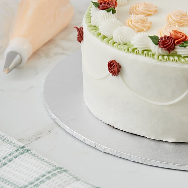 A close up of a Baker's Lane silver cake drum under a cake with roses on top.