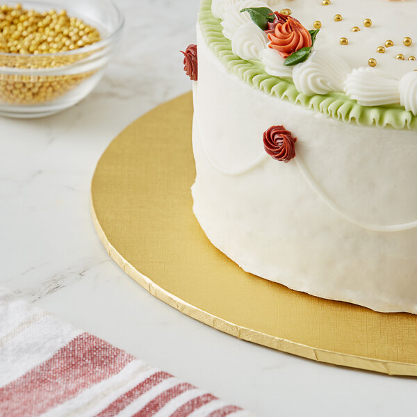 A Baker's Lane gold cake drum holding a cake with a flower on top.