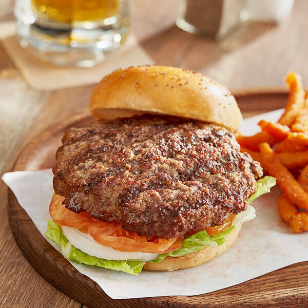 An AdvancePierre Pub Burger with lettuce, tomato, and cheese on a wooden plate with fries.