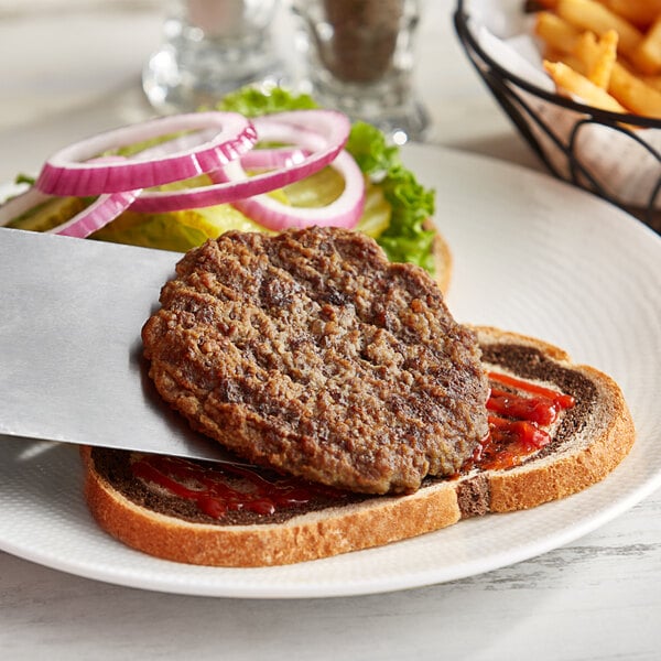 A plate with a knife and fork and a close-up of an AdvancePierre Pub Burger Patty served on it.