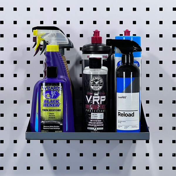 A Triton silver steel shelf with garment hanger holes holding cleaning supplies on a pegboard.