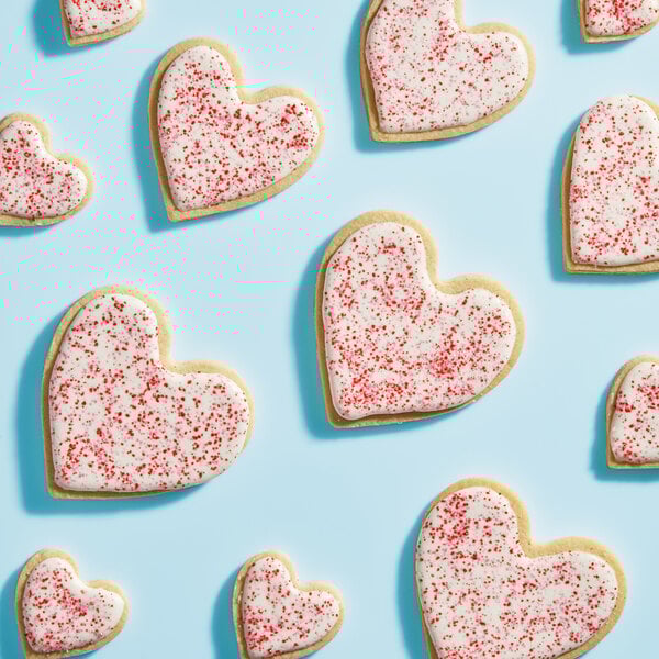 Heart shaped cookies with white frosting and Adourne Valentine Sanding Sugar sprinkles.